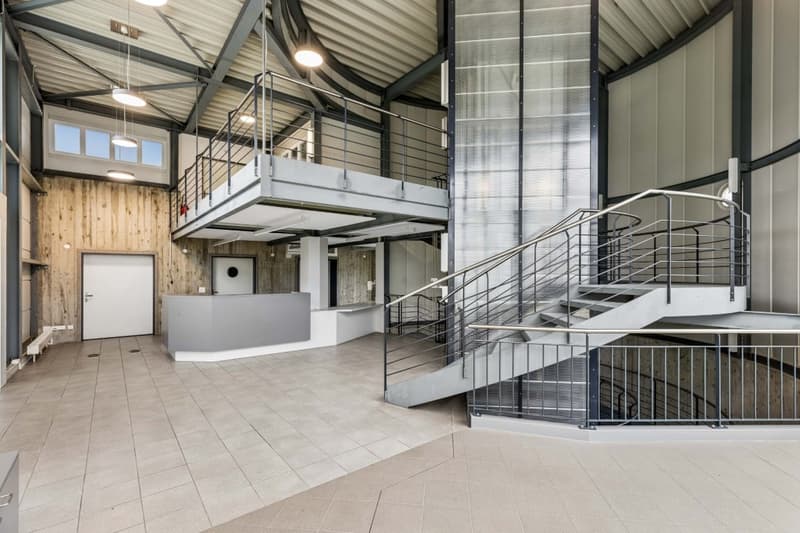 Industrial building with tiled floor, wooden wall, metal railings, staircase, and a balcony