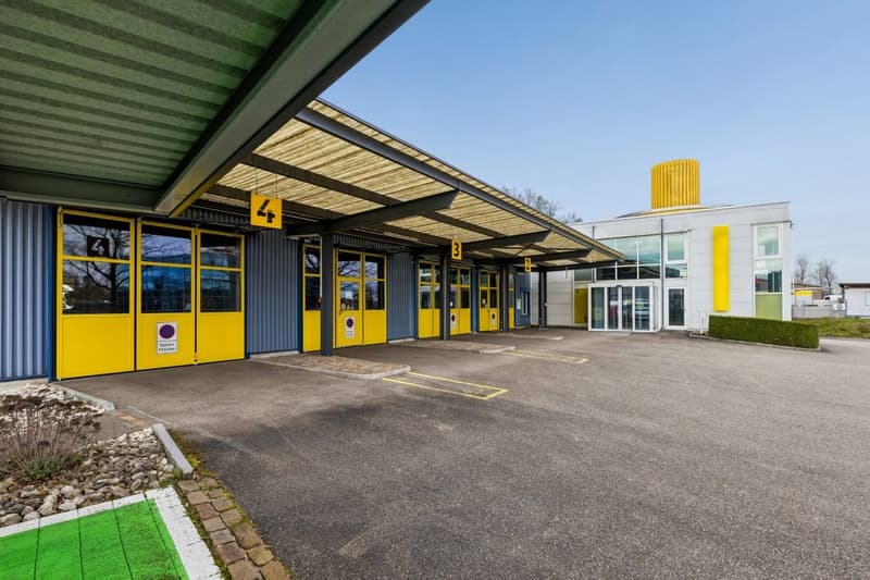 Parking building with yellow doors, number signs, and a large parking lot