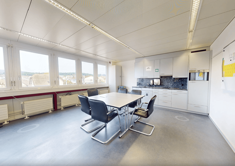 Modern conference room, large windows, desk, chairs, built-in kitchen with appliances
