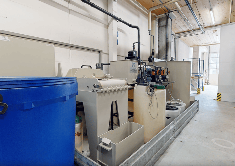 Water treatment facility with tanks, pipes, a blue barrel, machinery, and industrial equipment