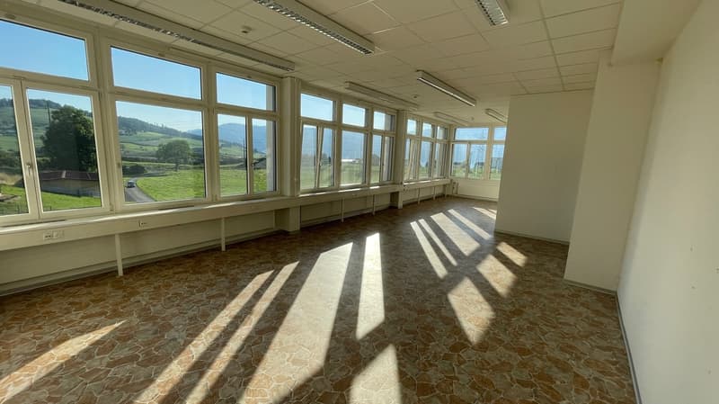 Large windows, stone floor, long white benches, exposed ceiling beams