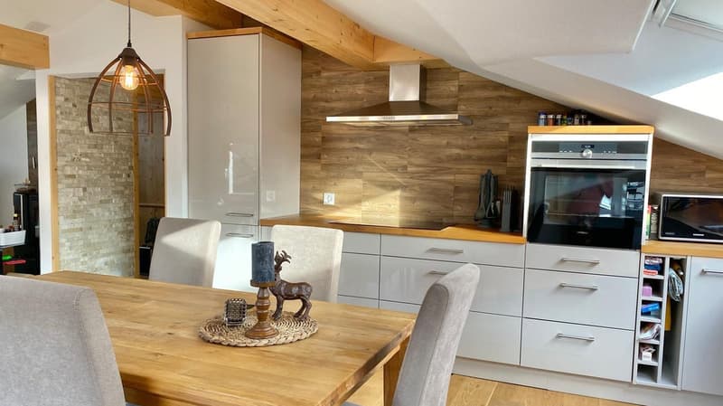 dining room, wooden table, white kitchen cabinets, tiled brick wall, modern light fixture, glass candle holder, ceramic deer figurine