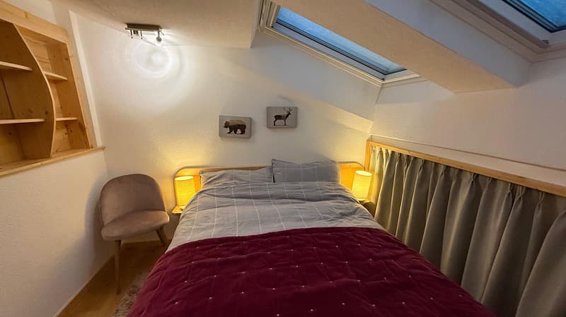 double bed, bedside lamps, chair, wooden shelf, picture frames, curtains, skylight