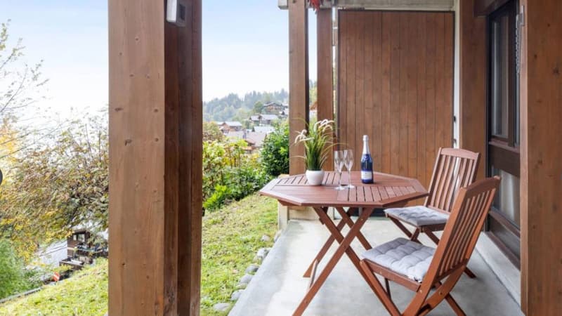 wooden balcony, table, chairs, bottle, wine glasses, plant, wooden walls, view of the mountains