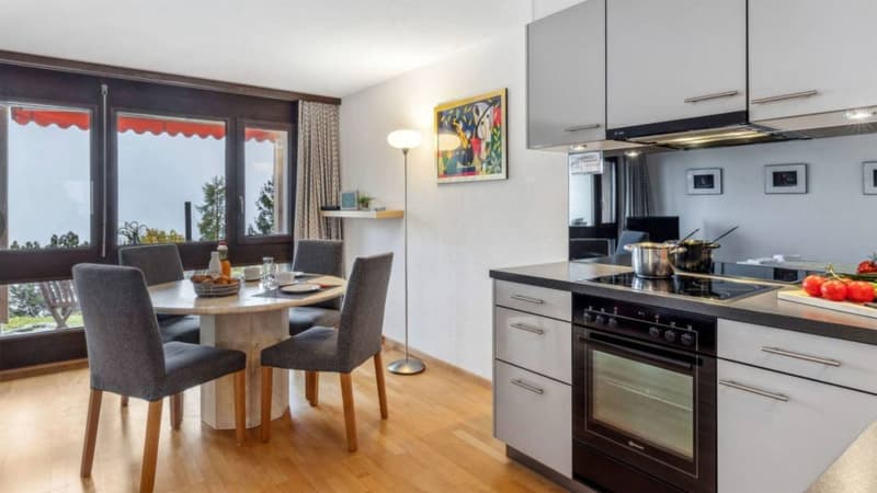 modern kitchen with dining area, wooden floor, large windows, table with chairs, gas stove, oven, cabinets, countertop, dining table, lamp, painting