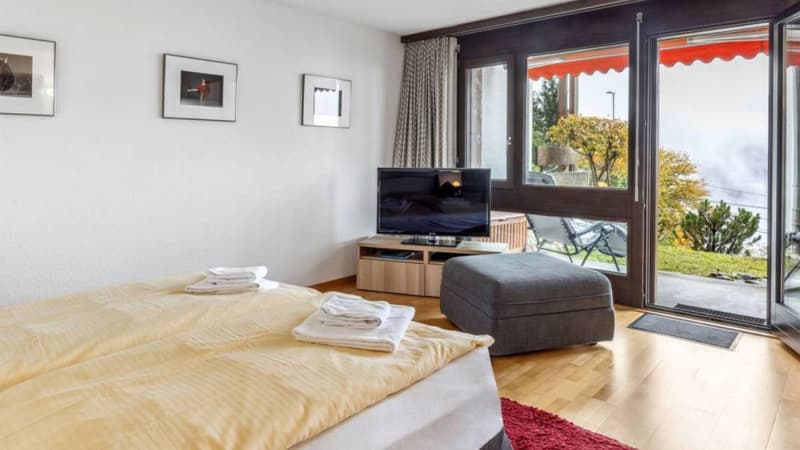 double bed, ottoman, TV, wooden floor, sliding glass doors, balcony, view of the outside