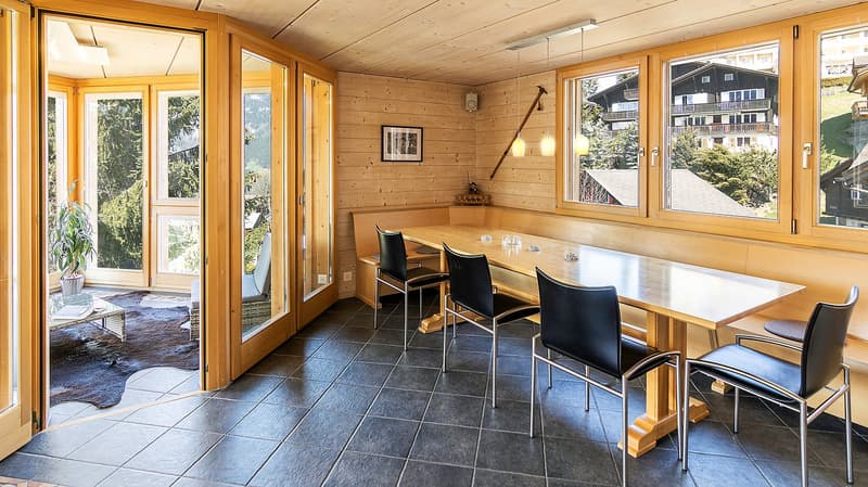 dining room, wooden table, black chairs, wooden walls, large windows, view of the outside