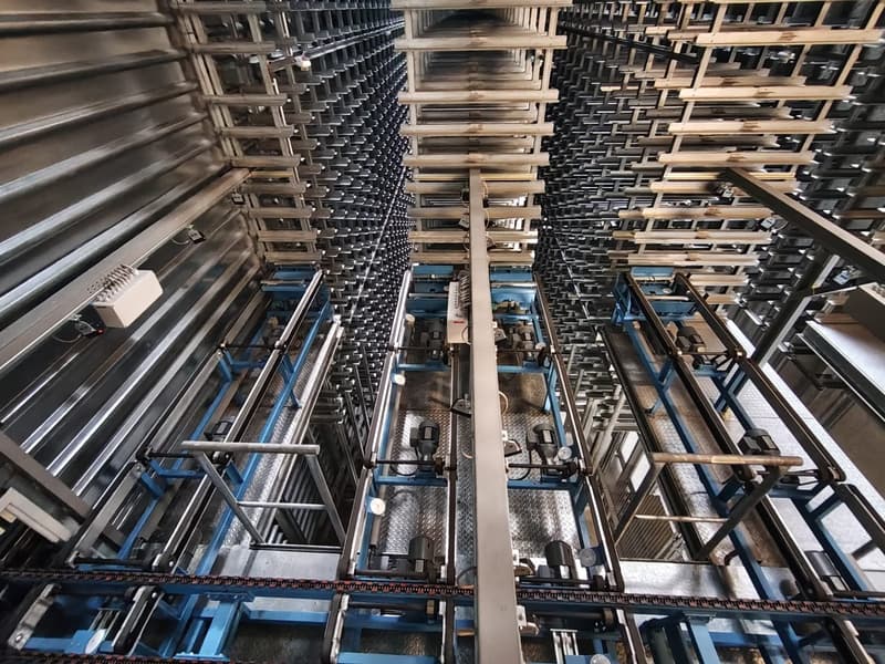 Industrial facility with multiple levels of storage racks, metal beams, and machinery components.