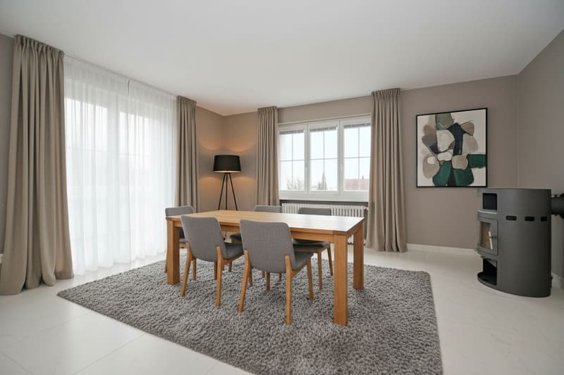 Dining area with wooden table, 4 chairs, lamp, and white and gray decor