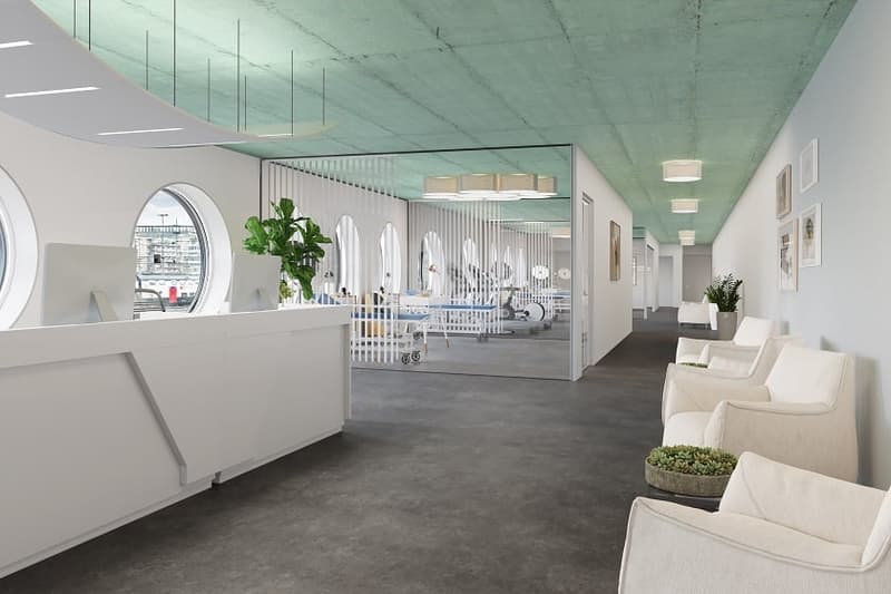 Spacious and modern office or commercial space with a reception area, comfortable seating, and glass partitions separating different sections. The space features a minimalist design with white walls, gray flooring, and recessed lighting. A dishwasher is v