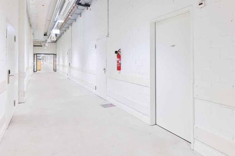 Long, white-walled hallway with a fire extinguisher mounted on the wall and a door labeled 'Lager'