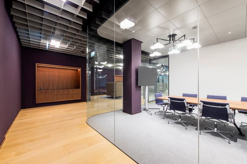 Meeting room with wooden table and chairs, glass walls, wooden floor, wooden cupboard