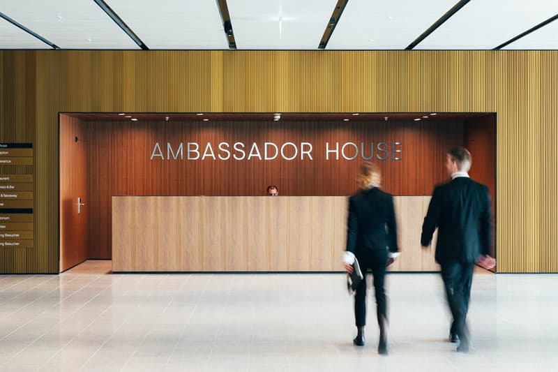 modern office entrance with wooden paneling, large sign reading 'AMBASSADOR HOUSE', and tiled floor