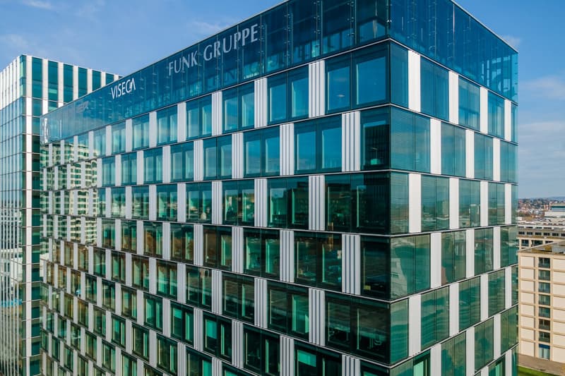 A modern, multi-story office building with a glass facade and the Funk Gruppe logo prominently displayed. The building has a sleek, contemporary design with a grid-like pattern of windows and glass panels.