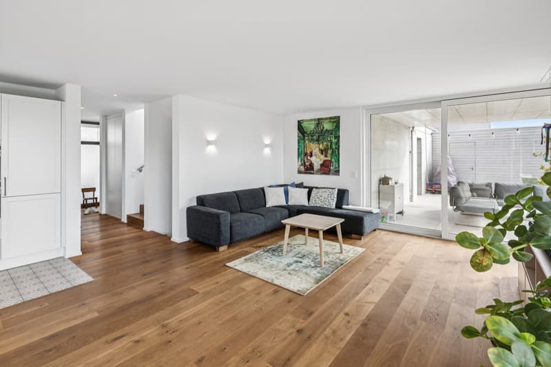 wooden floor, large sofa, center table, rug, kitchen on the left