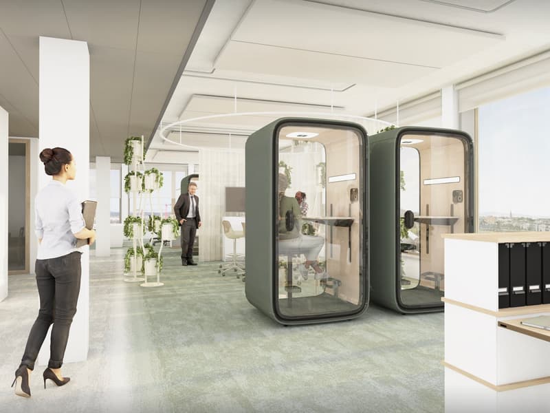a modern office with several work pods, carpeted floor, a large window, and a desk area.
