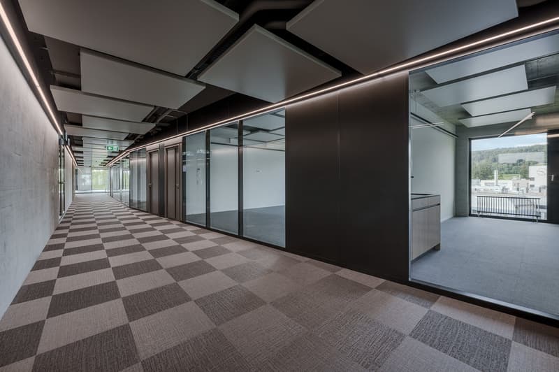 Empty hallway with checkered floor, glass walls, and ceiling panels