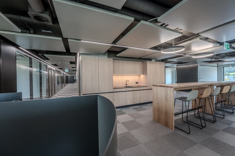 modern office space with wooden desk, chairs, glass walls, and ceiling lights