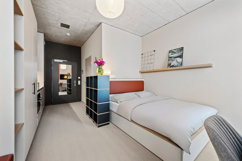 modern bedroom with single bed, wooden flooring, white walls, minimalist design, large shelves, bedside table, chair, floor lamp