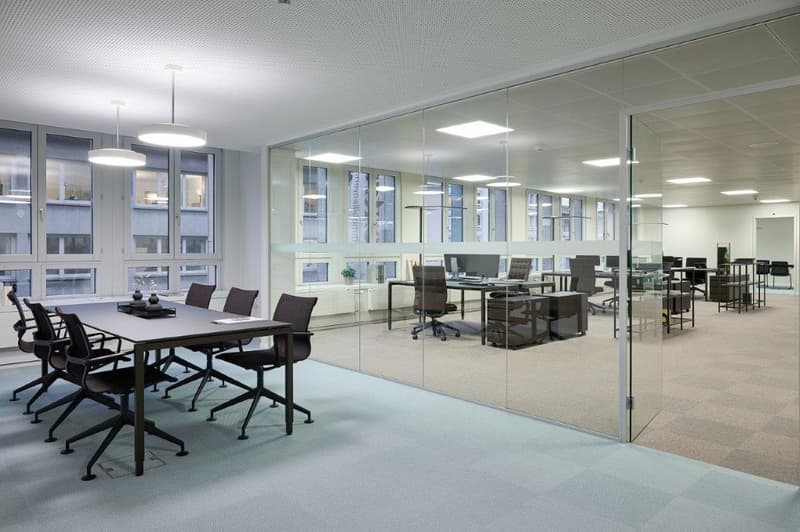 Large open office space with glass walls, conference table, desks, and chairs
