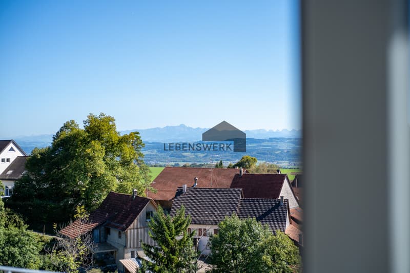 Die erhöhte Lage bietet einen weiten Blick über die grüne Landschaft bis zu den Alpen.