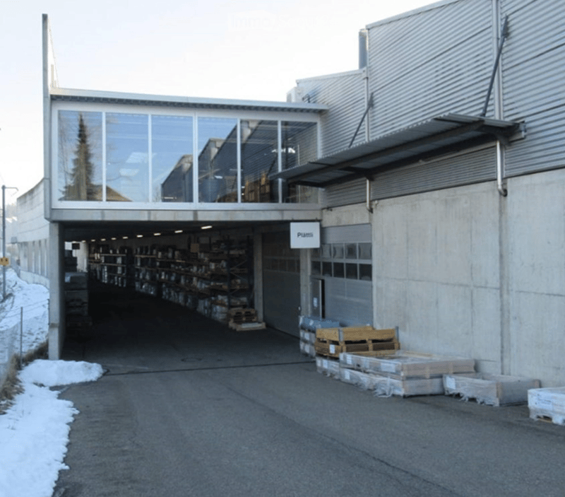 industrial building with raised ground floor, large windows, glass roof, interior shelves, parked boxes, concrete walls