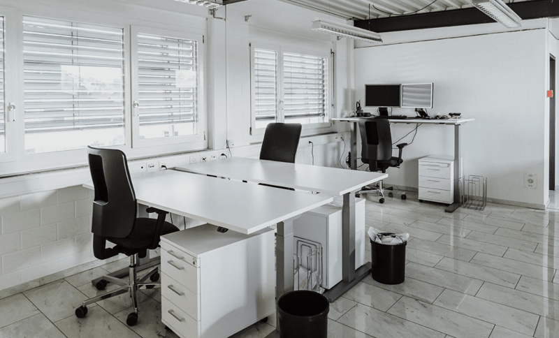 large desk, black office chairs, filing cabinets, monitors, white walls