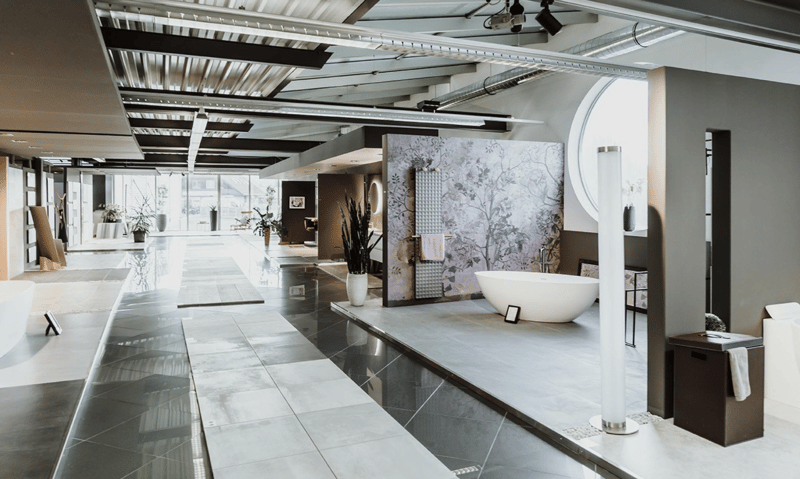 A hallway with modern tiles, a large curved window, a white bathtub, a potted plant, and various pieces of furniture.