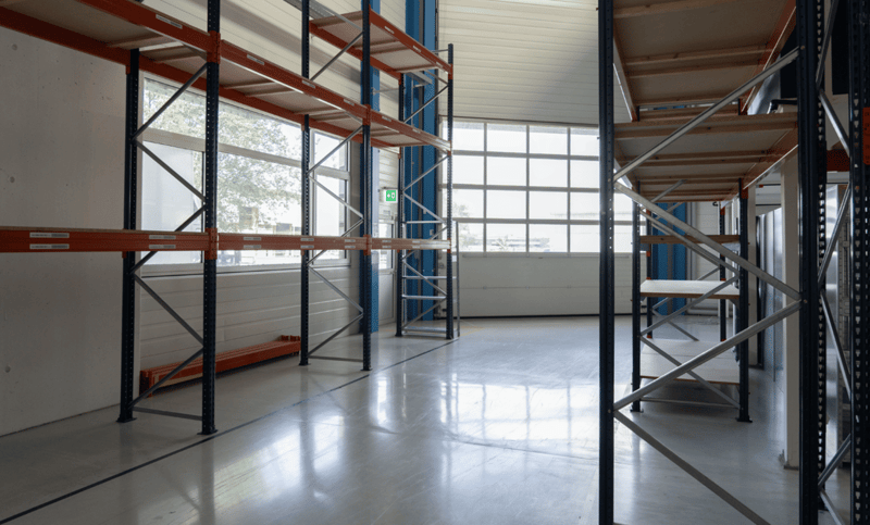 Empty room with a large window, metal racks, and industrial shelving.