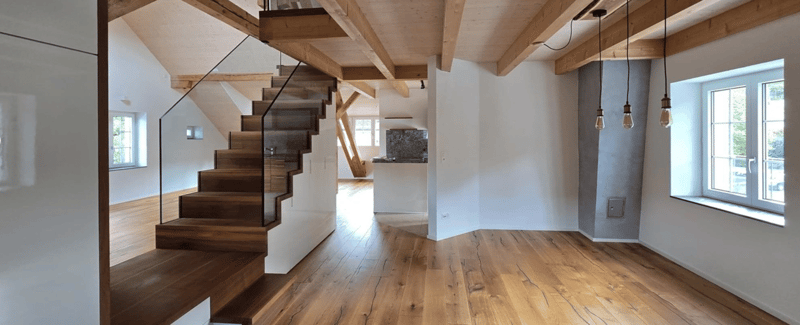 exposed wooden beams, hardwood flooring, glass railing on stairs, large windows with view