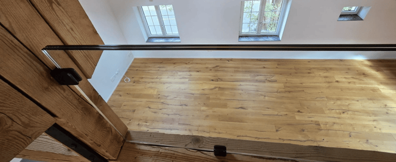 Wooden floor, glass door, white walls, three windows, slanted ceiling