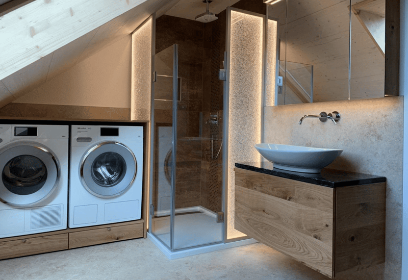 Two washing machines, wooden cabinets, large windows, sink, shower