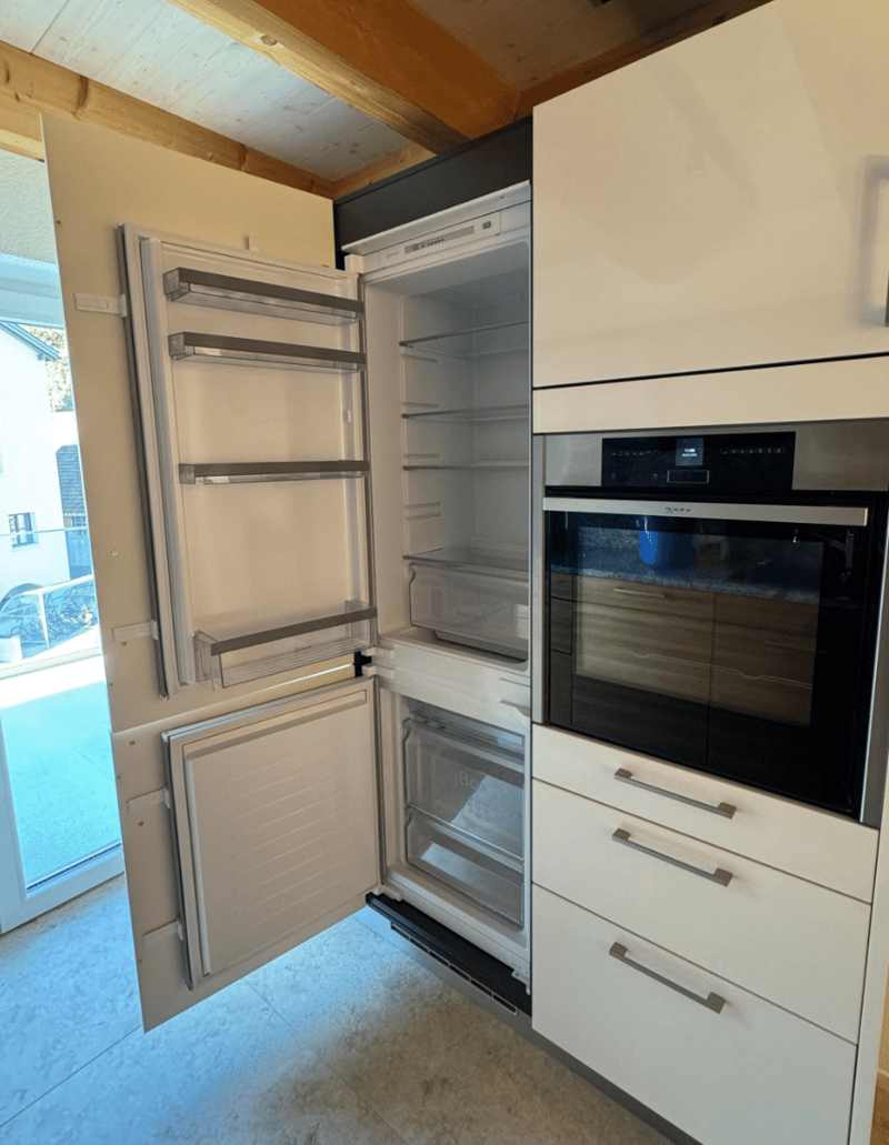 Open refrigerator with freezer, stainless steel oven, white cabinetry, dishwasher