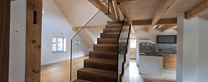 wooden stairs, wooden flooring, wooden beams, white walls, glass railing, kitchen