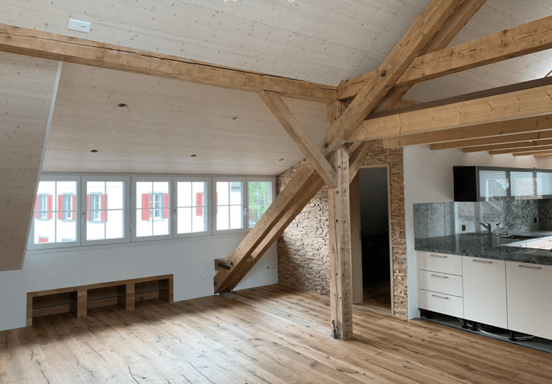 beamed ceilings, exposed wooden beams, hardwood floors, large windows with red shutters, kitchen area with modern cabinetry and granite countertops
