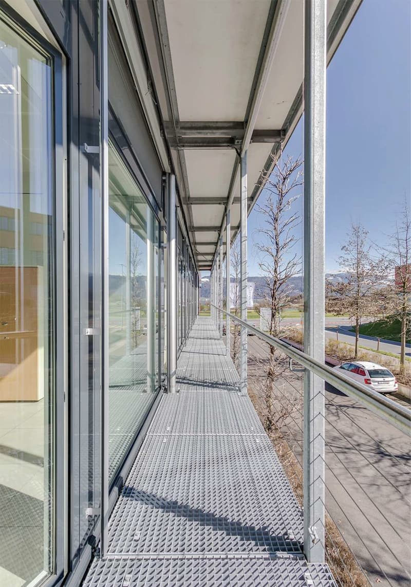 modern building with glass walls, metal floor, metal railings, large windows, metal beams