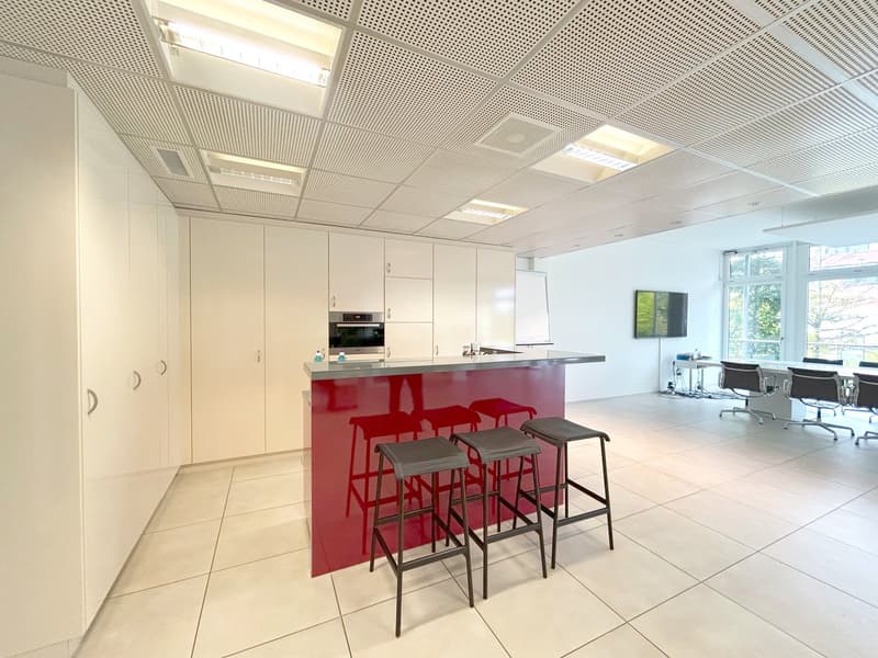 modern kitchen with red counter, white cabinets, built-in oven, 3 stools, tiled floor, white walls, ceiling lights, whiteboard, TV, dining table, chairs