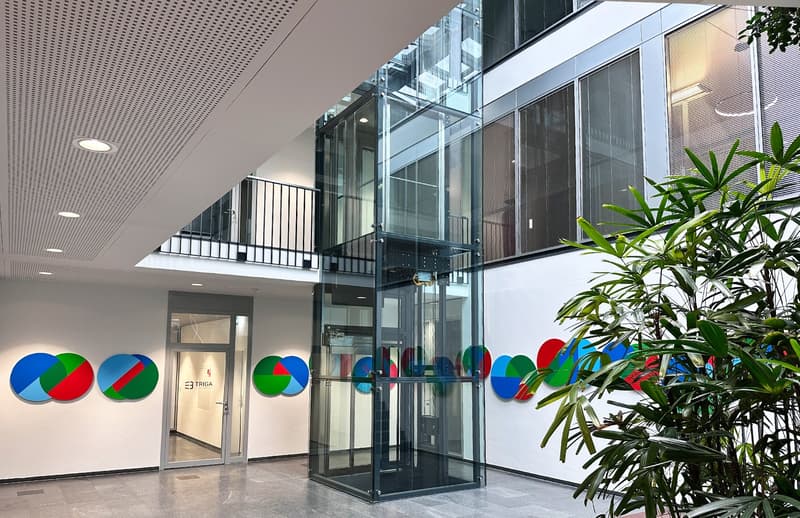 modern office building, glass elevator, white walls, colorful wall art, glass doors, plant