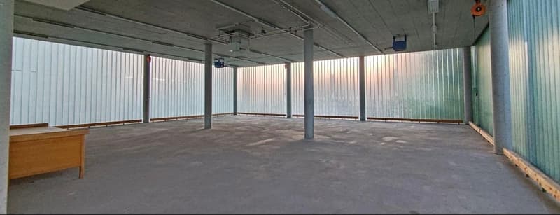 empty room, concrete floor, steel columns, wooden desk, white slat walls, glass windows