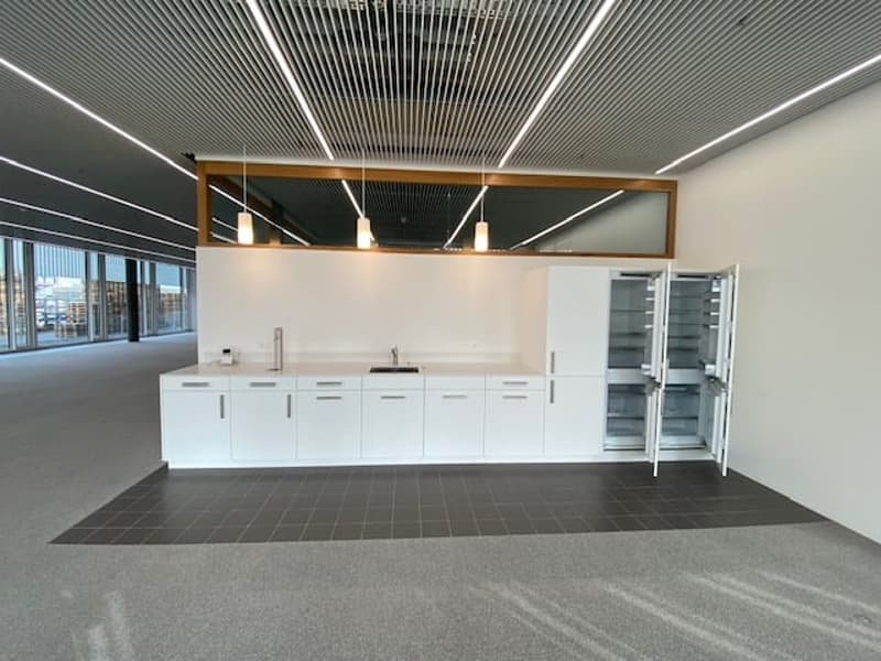 Commercial kitchen with open refrigerator, countertops, cabinets, sink and faucet.