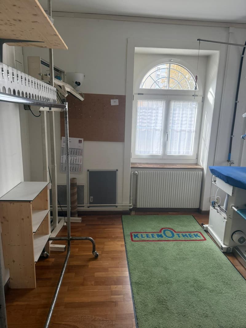 an empty room, a wooden shelf, a white radiator, a window, an arch shape, and a wooden floor