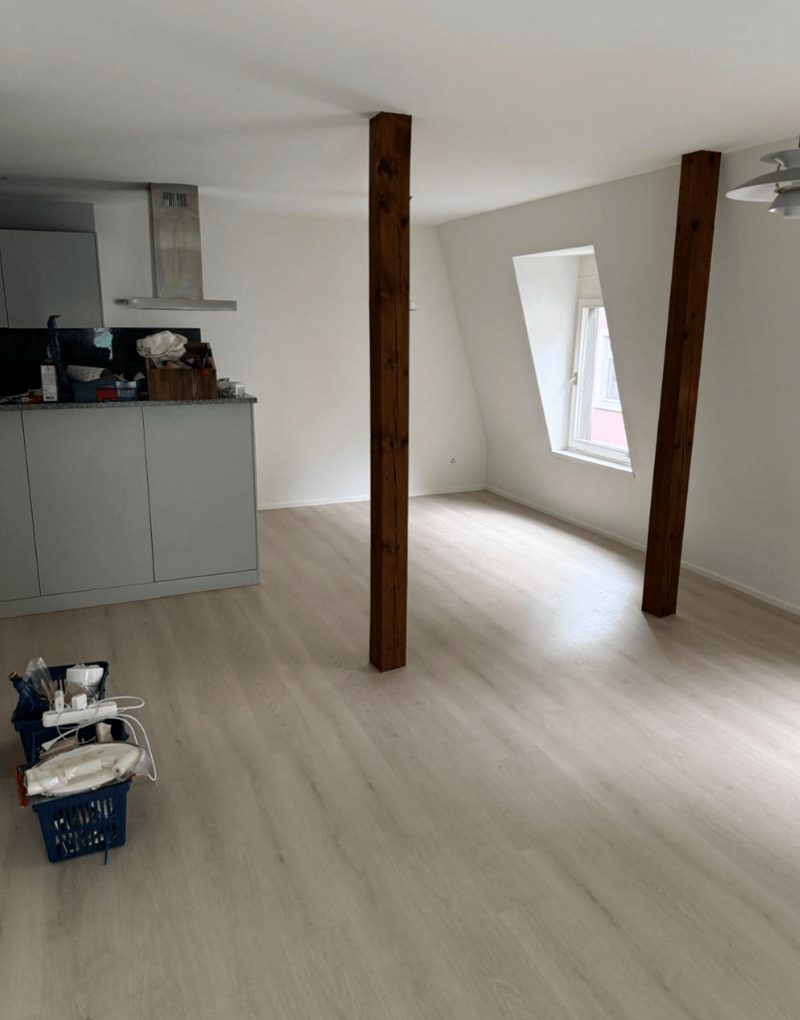 Empty room, wooden floor, wooden support columns, kitchen counter, small attic window