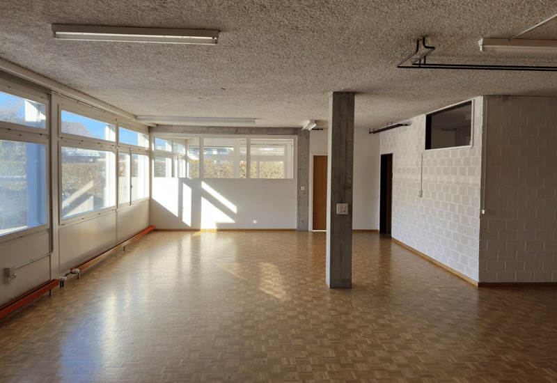 Open room with parquet floor, windows, column, ceiling lamps