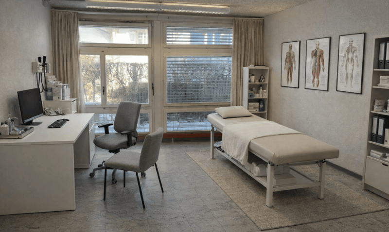 Desk, chair, bed, window, shelves, medical diagrams on the wall.