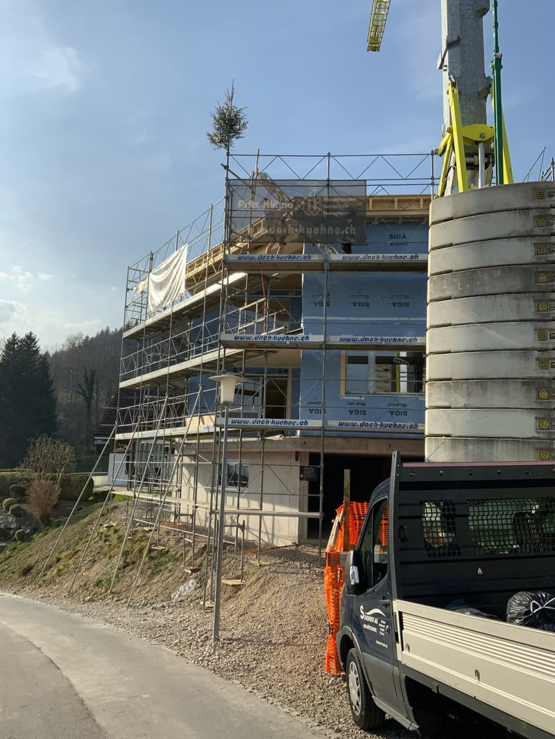 Building under construction, scaffolding, crane, road, trees, mountains