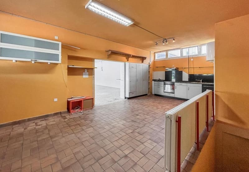 Empty room, tiled floor, orange walls, cabinets, shelves, open door leading to another room, modern kitchen with appliances, and a radiator.