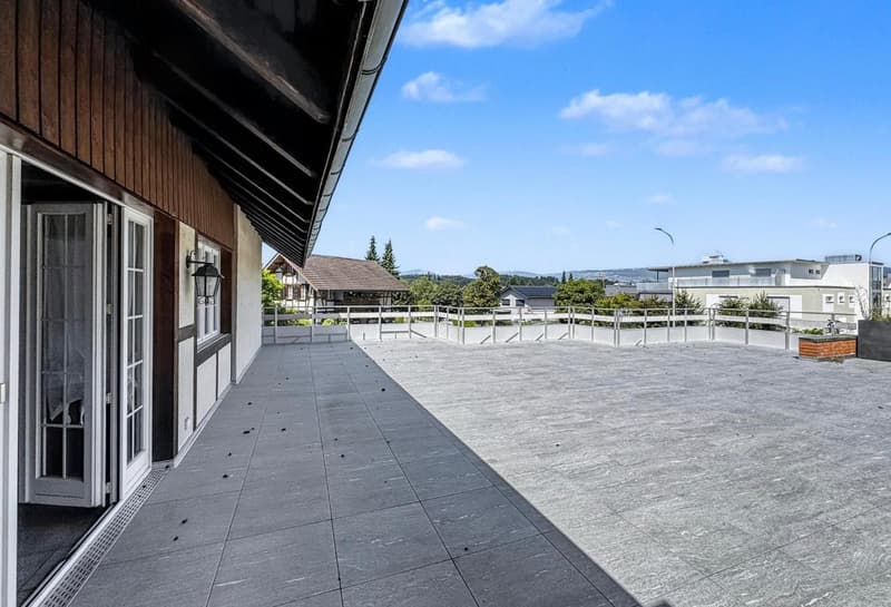 Roof terrace with tiled flooring and fence, glass doors, view of buildings and landscape