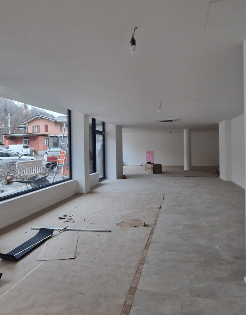 empty room, with large window, pillar, empty floor, a pile of material on the ground
