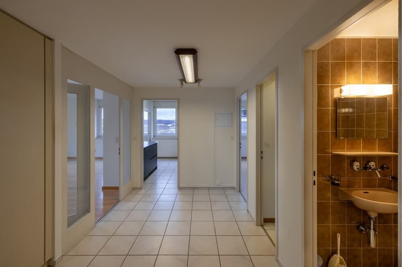 corridor with white tiles, mirror, sink, power outlets, hallway light