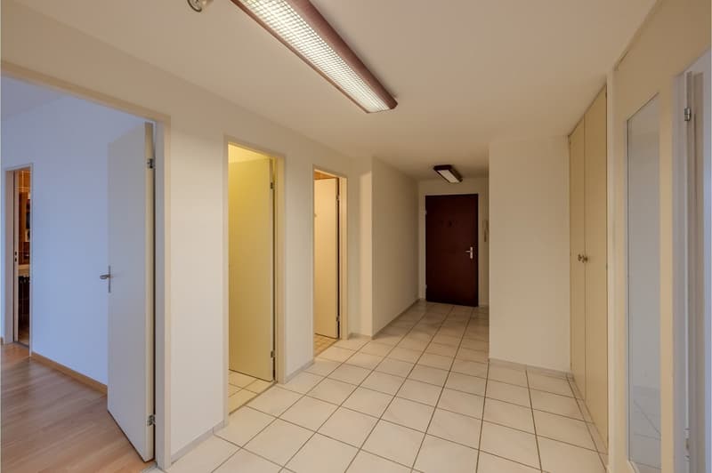 Empty hallway with tiled flooring, open doors, ceiling lights, wooden flooring in the entrance